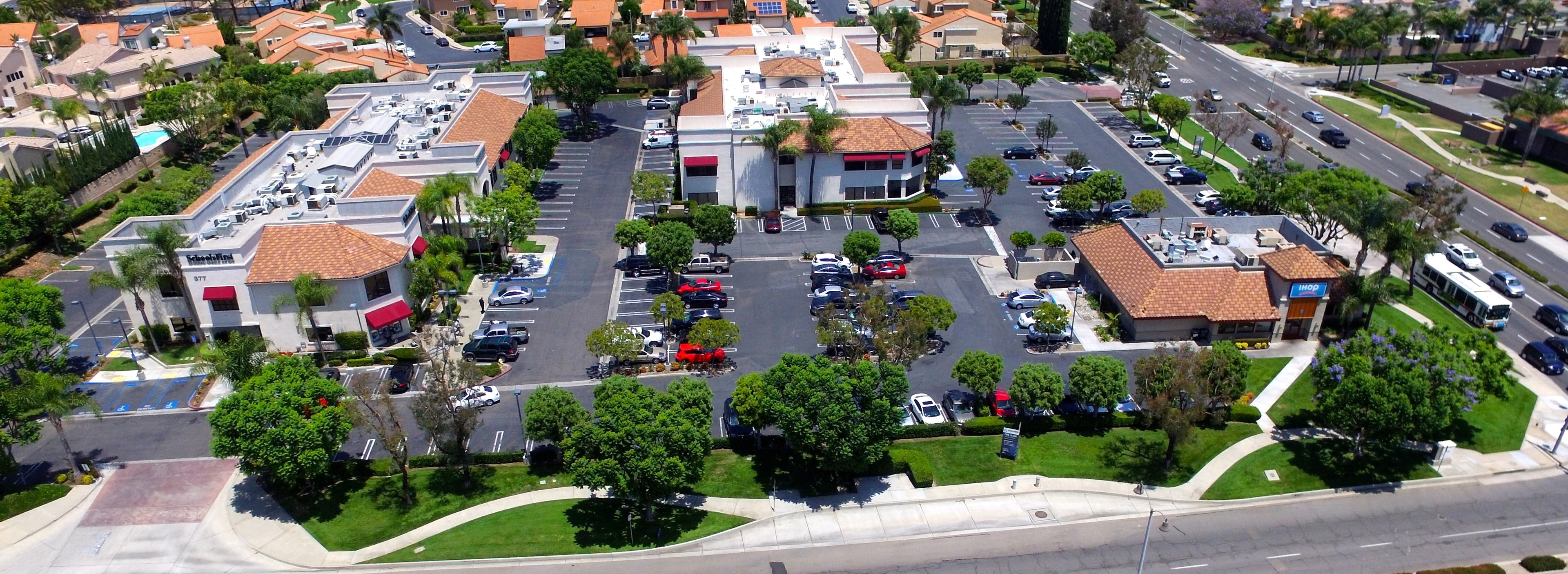 Aerial view of commercial shopping center with manicured parking lot landscaping maintained by Kirton's Landscape Maintenance, Inc.