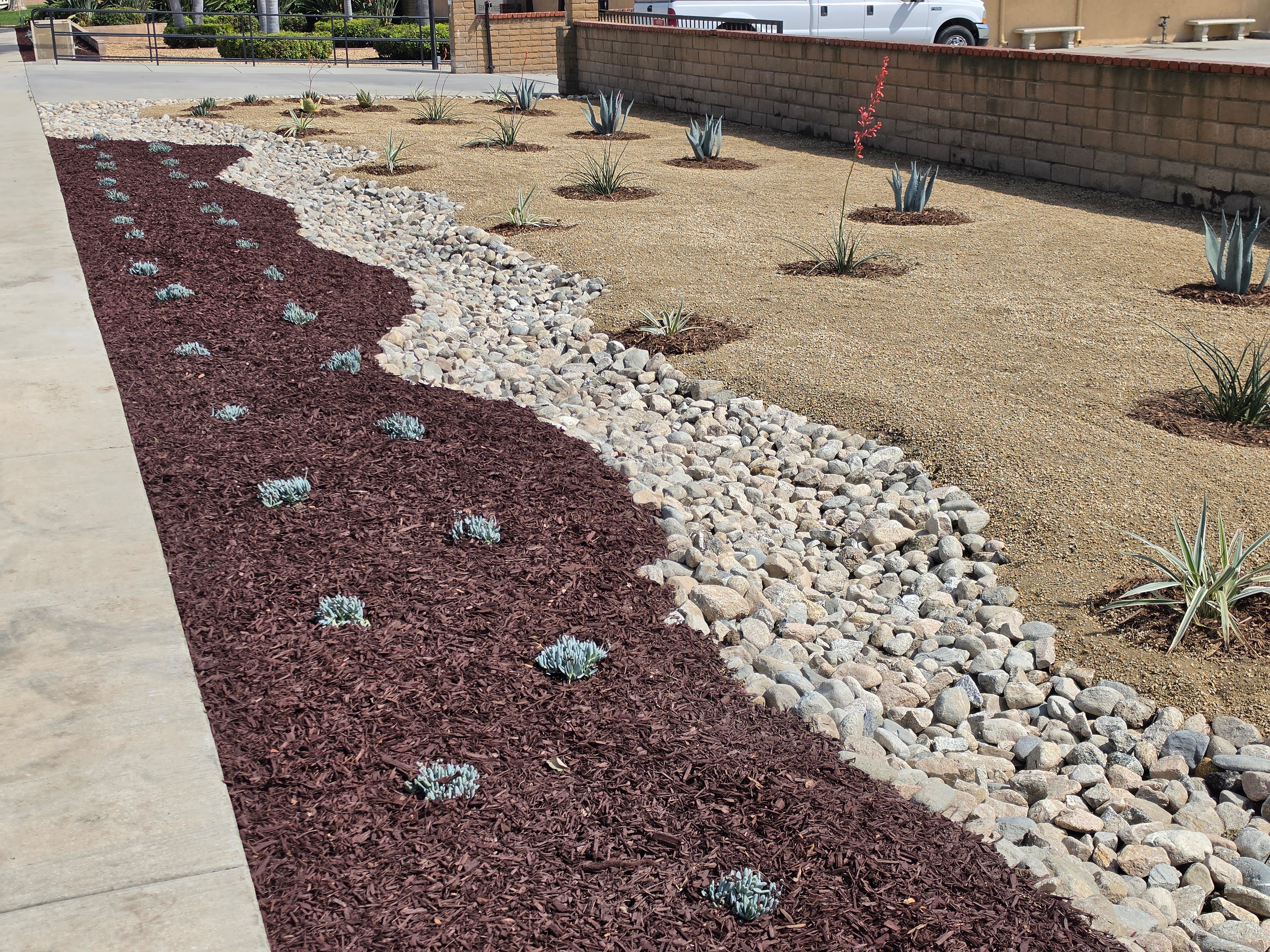 Drought-tolerant xeriscape landscape with decorative mulch, river rocks, and agave plants installed by Kirton's Landscape Maintenance, Inc.